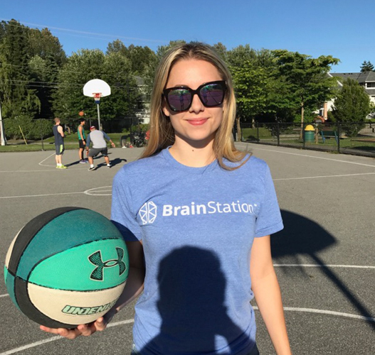 girl in brainstation t-shirt playing basketball