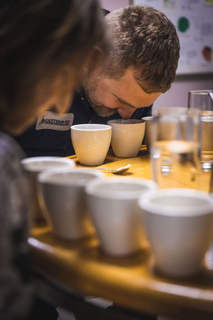 A coffee taster leaning over a cup to smell the coffee during the cupping process