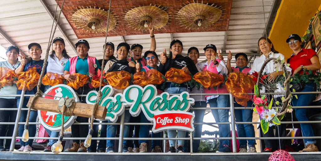 A group of women waving from the balcony of a coffee shop in Colombia