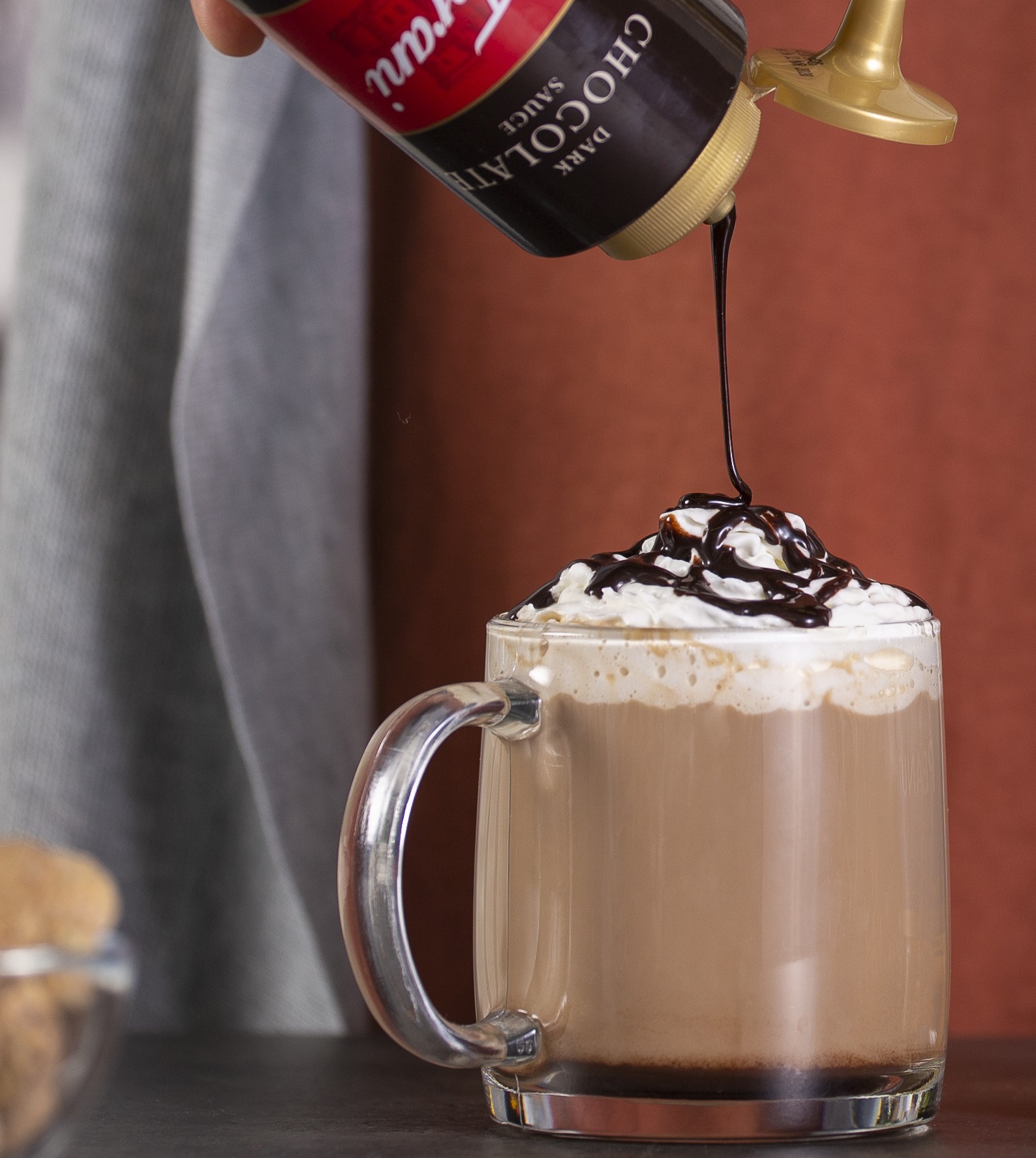 Torani Dark Chocolate Sauce drizzling over a hot chocolate with whipped cream.